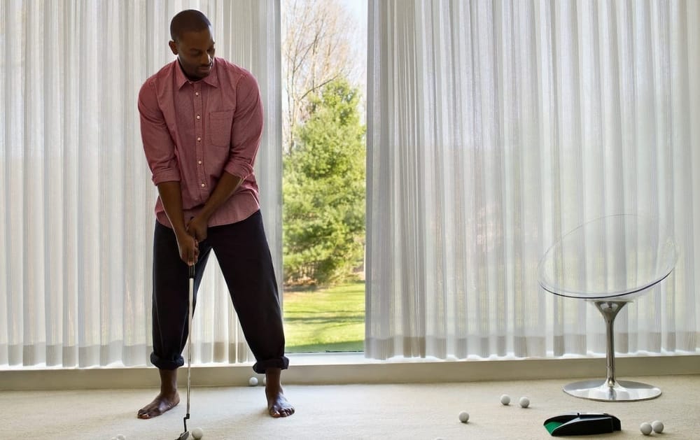 A man plays golf in his at-home man cave